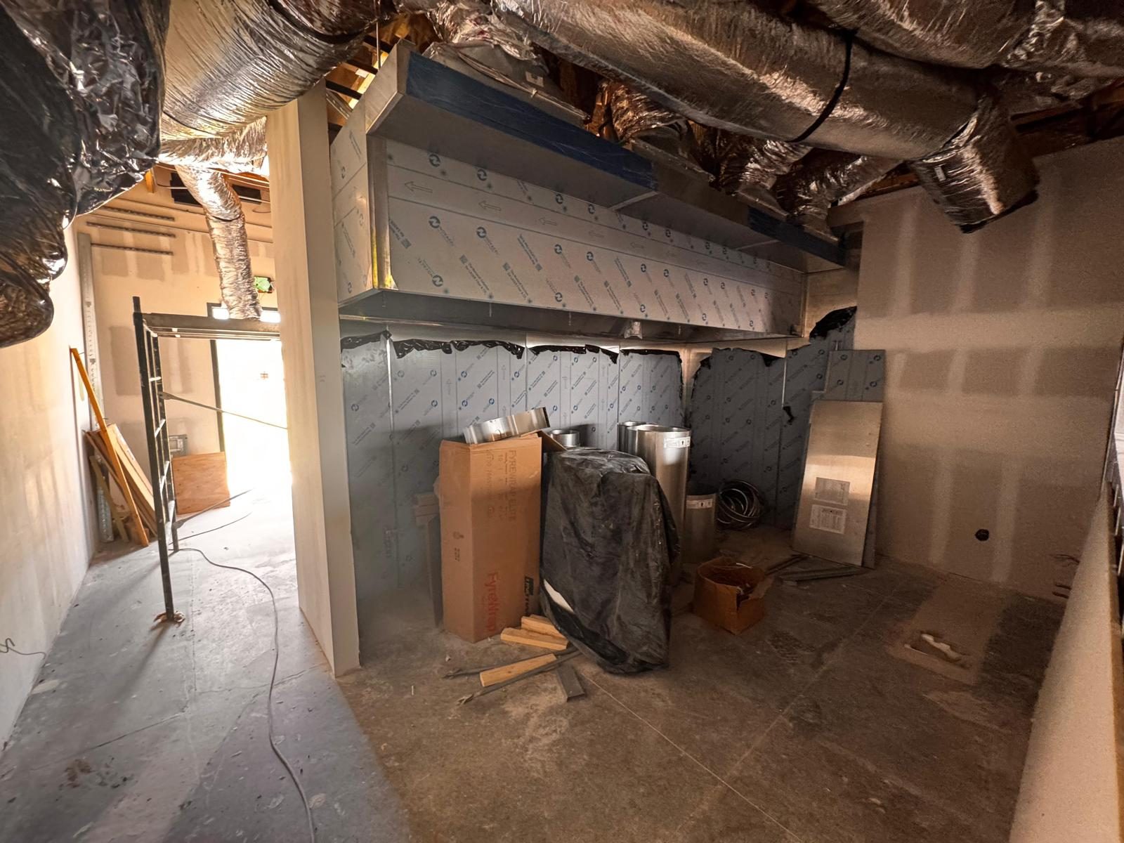 Stainless kitchen hood installed with ductwork overhead